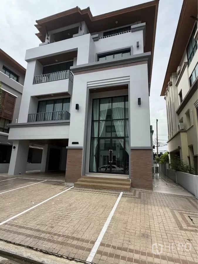 带办公室的家 出租在Wang Thonglang, Bangkok - 现代四层居家办公楼外观，超高玻璃入口与划线停车位。