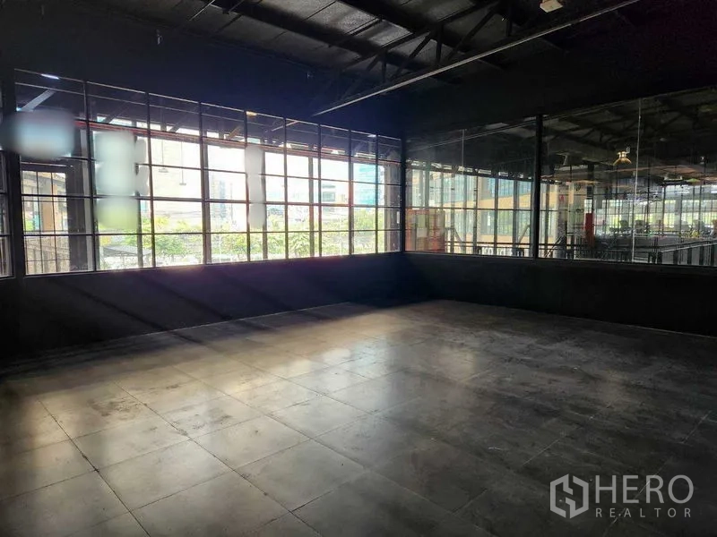 Retail Space for rent in Khlong Toei, Bangkok - Loft-style retail shell with large grid windows, dark walls and tiled flooring filled with natural light.