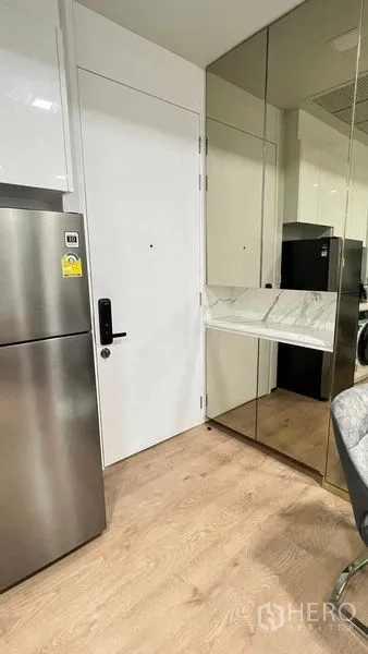 Condominium for rent in Watthana, Bangkok - Entry to kitchen with stainless refrigerator and mirrored console panel.