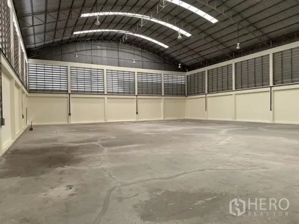 Warehouse for rent in Mueang Samut Sakhon, Samut Sakhon - Spacious warehouse interior with high arched steel roof, skylights, louvered ventilation and smooth concrete floor.