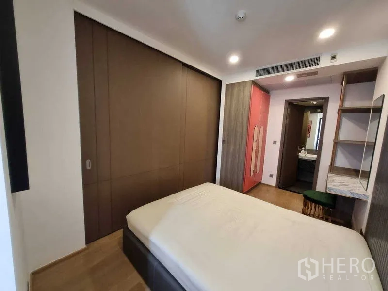 Condominium for rent in Bang Rak, Bangkok - Bedroom with sliding closets, red wardrobe and doorway to bathroom.