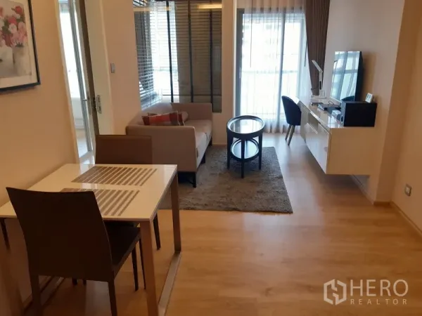 Condominium for rent in Watthana, Bangkok - Open-plan living and dining area with sofa, TV unit, work desk and balcony doors in a Watthana condo.