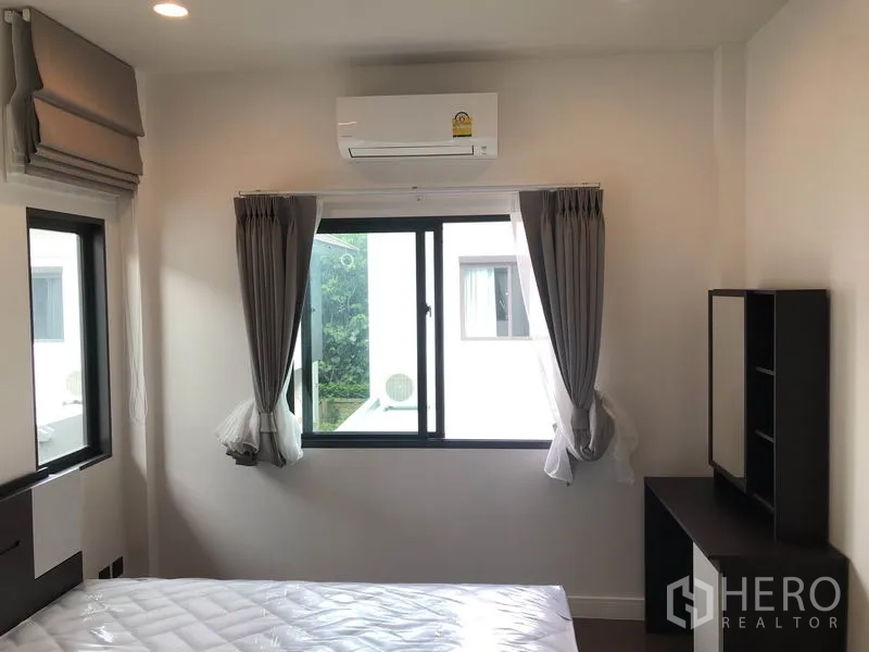 Detached House for rent or sale in Bang Kapi, Bangkok - Cozy secondary bedroom with bed, windows and air conditioner.