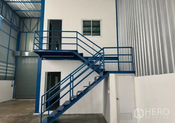 Warehouse for rent in Lam Luk Ka, Pathum Thani - Metal staircase leading to the upper office level within the warehouse.