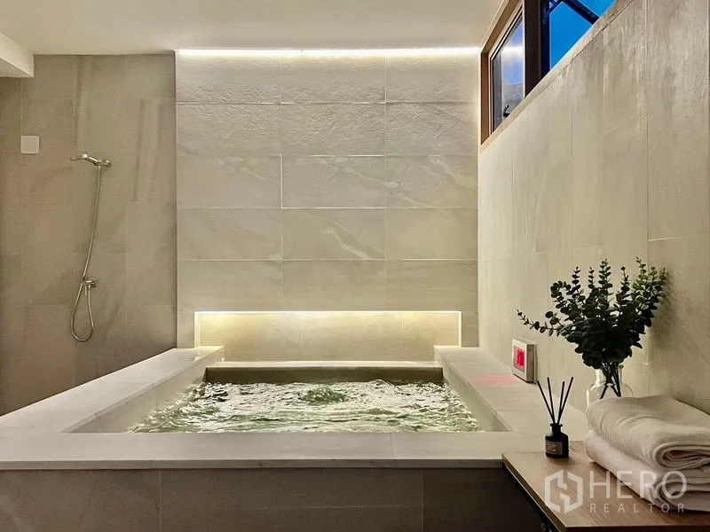 Townhouse for rent or sale - Spa bathroom featuring deep soaking tub, ambient lighting and decorative greenery.