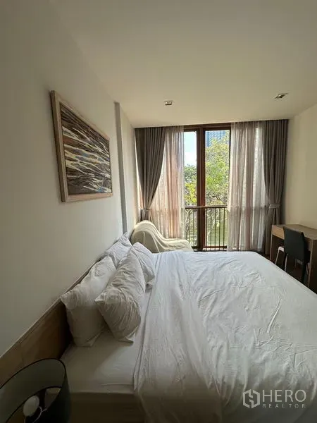 Condominium for rent in Watthana, Bangkok - Bright master bedroom with large window and small balcony, plus desk and armchair.