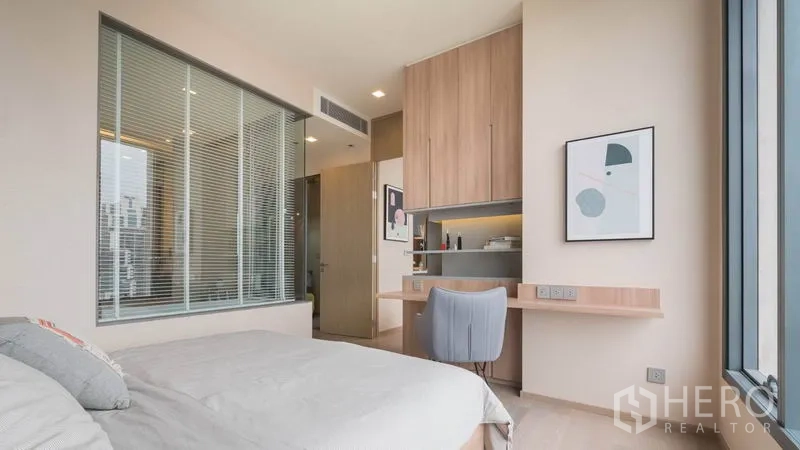 公寓 出租在Watthana, Bangkok - 主卧配大窗、内置书桌与衣柜，可望向带玻璃墙的浴室。