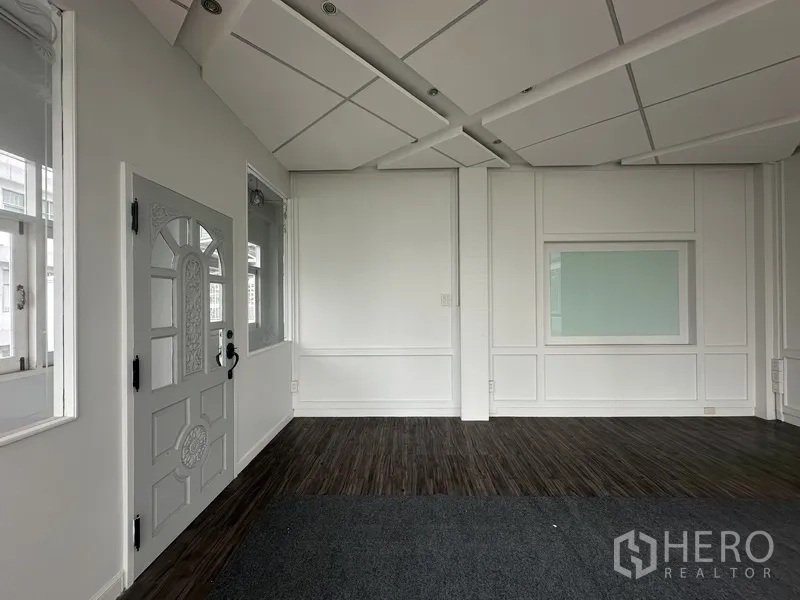 Retail Space for rent in Bang Rak, Bangkok - Bright retail room with dark flooring, decorative wall panels, and window.