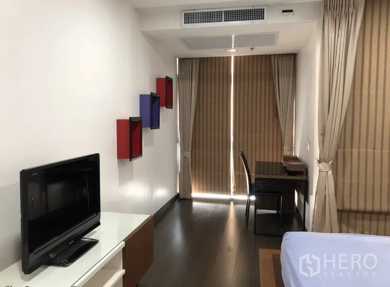 公寓 出租在Khlong Toei, Bangkok - 卧室内设电视、靠窗书桌与遮光窗帘。