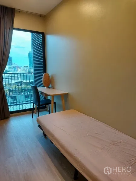 Condominium for rent in Phaya Thai, Bangkok - Compact study or guest room with single bed, work desk and balcony city outlook.