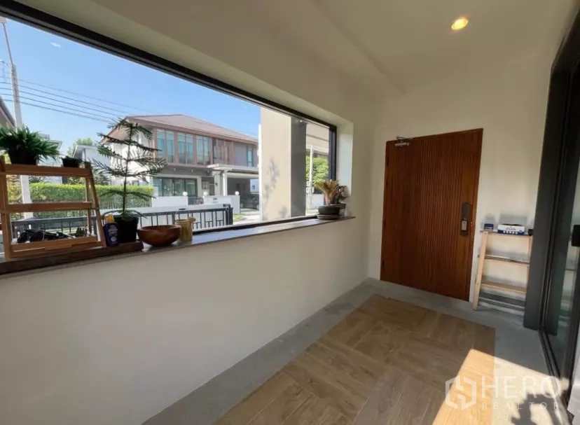 独立式住宅 出租在Prawet, Bangkok - 入户玄关设长幅观景窗、木质大门与置物架。
