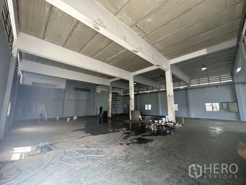 Factory for rent or sale in Bang Bua Thong, Nonthaburi - Open warehouse space with multiple columns, industrial lighting and ventilated upper windows.