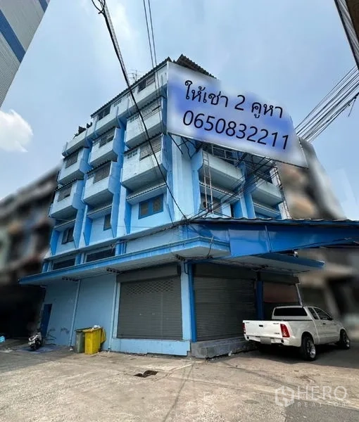อาคารพาณิชย์ ให้เช่าในBang Na, Bangkok - อาคารพาณิชย์มุมตึกสูงห้าชั้น สีฟ้า มีระเบียงและประตูเหล็กม้วน ย่านบางนา