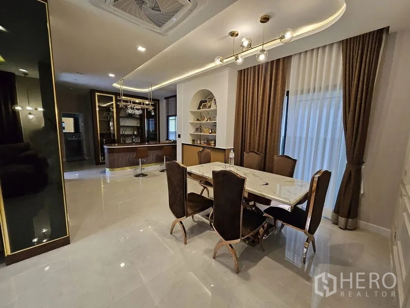 独立式住宅 出售在Mueang Pathum Thani, Pathum Thani - 开放式餐区，石材餐桌、金色吊灯与内置吧台柜。