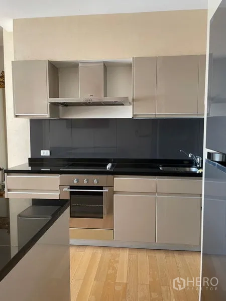 Condominium for rent in Watthana, Bangkok - Sleek built-in kitchen with oven, cooktop and glossy cabinets.