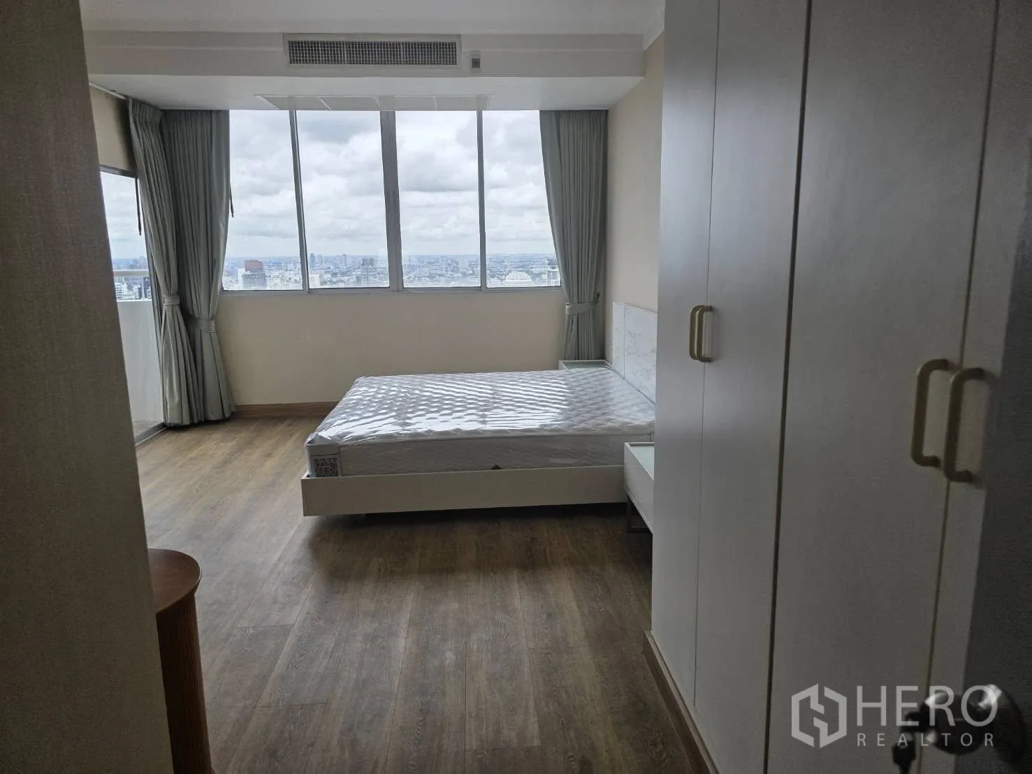 Condominium for rent in Khlong Toei, Bangkok - Master bedroom with wardrobe and panoramic city views through wide windows.