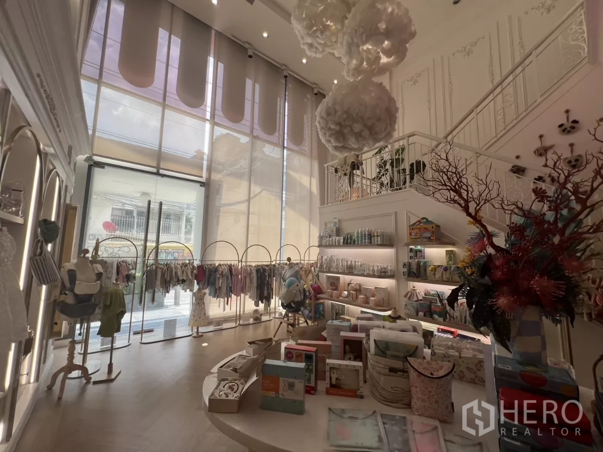 Retail Space for rent in Watthana, Bangkok - Double-height retail interior with floor-to-ceiling windows, staircase and display racks.
