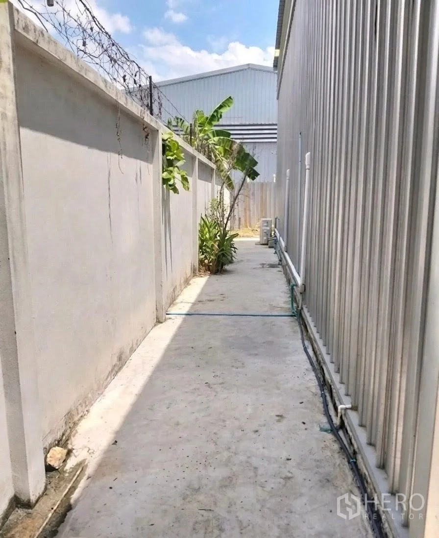 仓库 for rent in Don Mueang, Bangkok - 建筑后方服务通道，设有围墙、防护铁丝与外部管线。