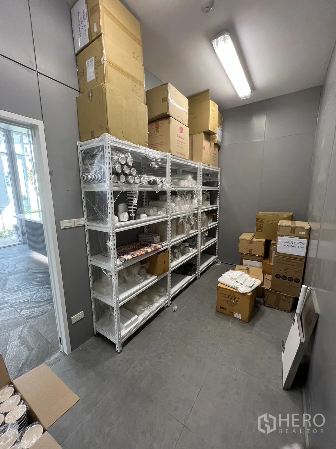 Retail Space for rent in Khlong Toei, Bangkok - Back-of-house storage room with metal shelving and tiled floors for inventory.