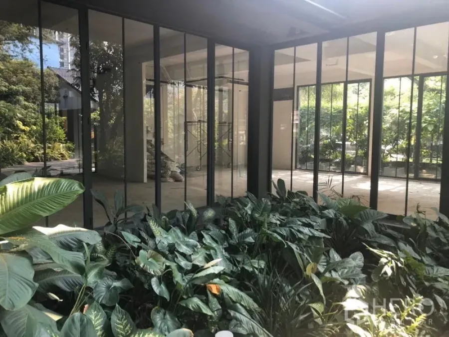 Office Space for rent in Khlong Toei, Bangkok - Open-plan office enclosed by floor-to-ceiling glass with views to a lush garden courtyard.