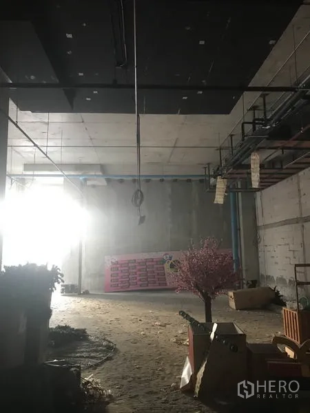 Retail Space for rent in Khlong Toei, Bangkok - Large shell retail area with hanging conduits and natural light entering from the side.