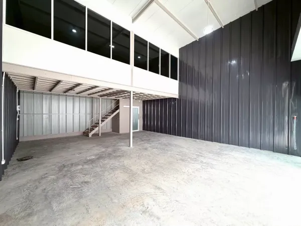 Warehouse for rent in Suan Luang, Bangkok - Open storage bay showing steel walls, mezzanine level with stair access and bright lighting.