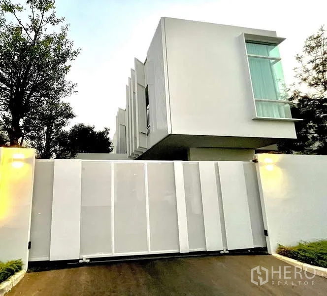 Detached House for rent or sale in Bang Phli, Samut Prakan - Contemporary white detached house facade with high fence and sliding gate.