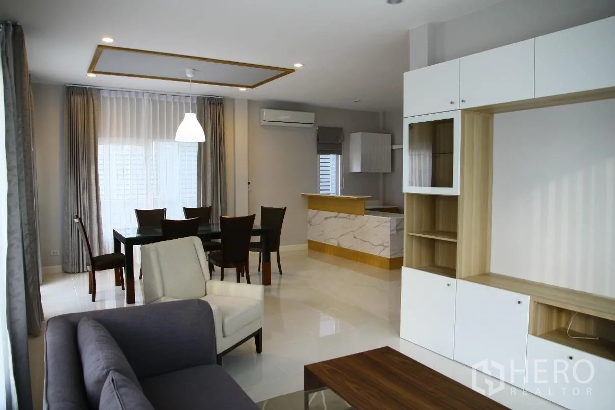 บ้าน ให้เช่าหรือขายในBang Na, Bangkok - โถงรับแขกและรับประทานอาหารแบบเปิดโล่ง พร้อมโซฟา โต๊ะทานอาหาร ตู้บิลท์อิน และเคาน์เตอร์หินอ่อน ใกล้หน้าต่างบานใหญ่