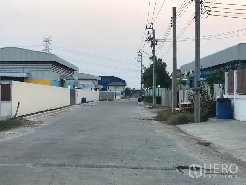 Factory for sale in Pak Kret, Nonthaburi - Access road through an organized industrial area with warehouses on both sides.