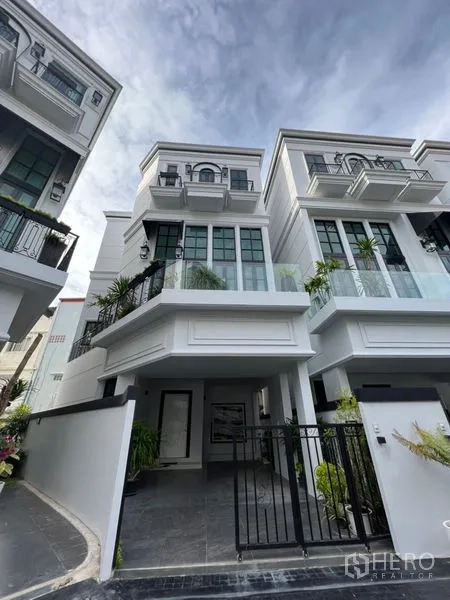 带办公室的家 出租或出售在Watthana, Bangkok - 三层白色住办公房外观，带大窗与可上锁车棚。