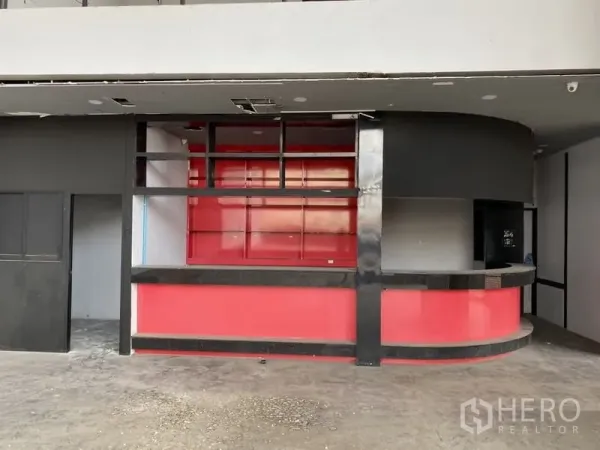 展厅 出租在Lat Phrao, Bangkok - 一层接待区，配红色弧形吧台与开放式置物架。