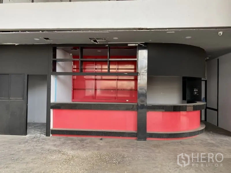 展厅 出租在Lat Phrao, Bangkok - 一层接待区，配红色弧形吧台与开放式置物架。