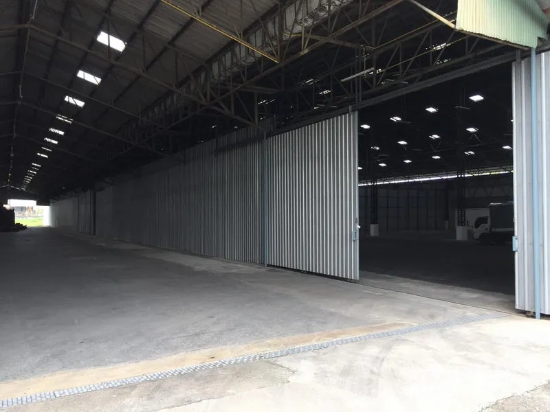 Warehouse for rent in Mueang Pathum Thani, Pathum Thani - Large sliding metal doors with covered loading area allowing truck access to the warehouse.