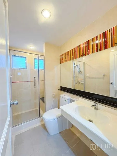 Townhouse for rent in Phra Khanong, Bangkok - Modern bathroom with glass shower enclosure and large mirror.