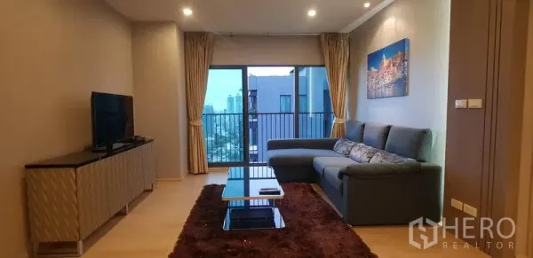 公寓 出租在Khlong Toei, Bangkok - 采光良好的客厅，转角沙发、电视柜与阳台城市景观