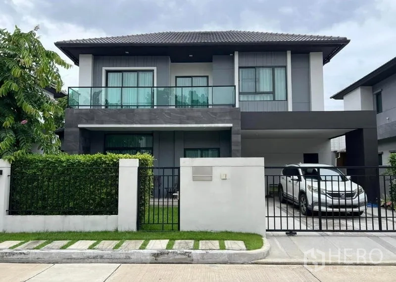 Detached House for sale in Khan Na Yao, Bangkok - Modern two-storey detached house with glass balcony, gated front yard and covered carport.