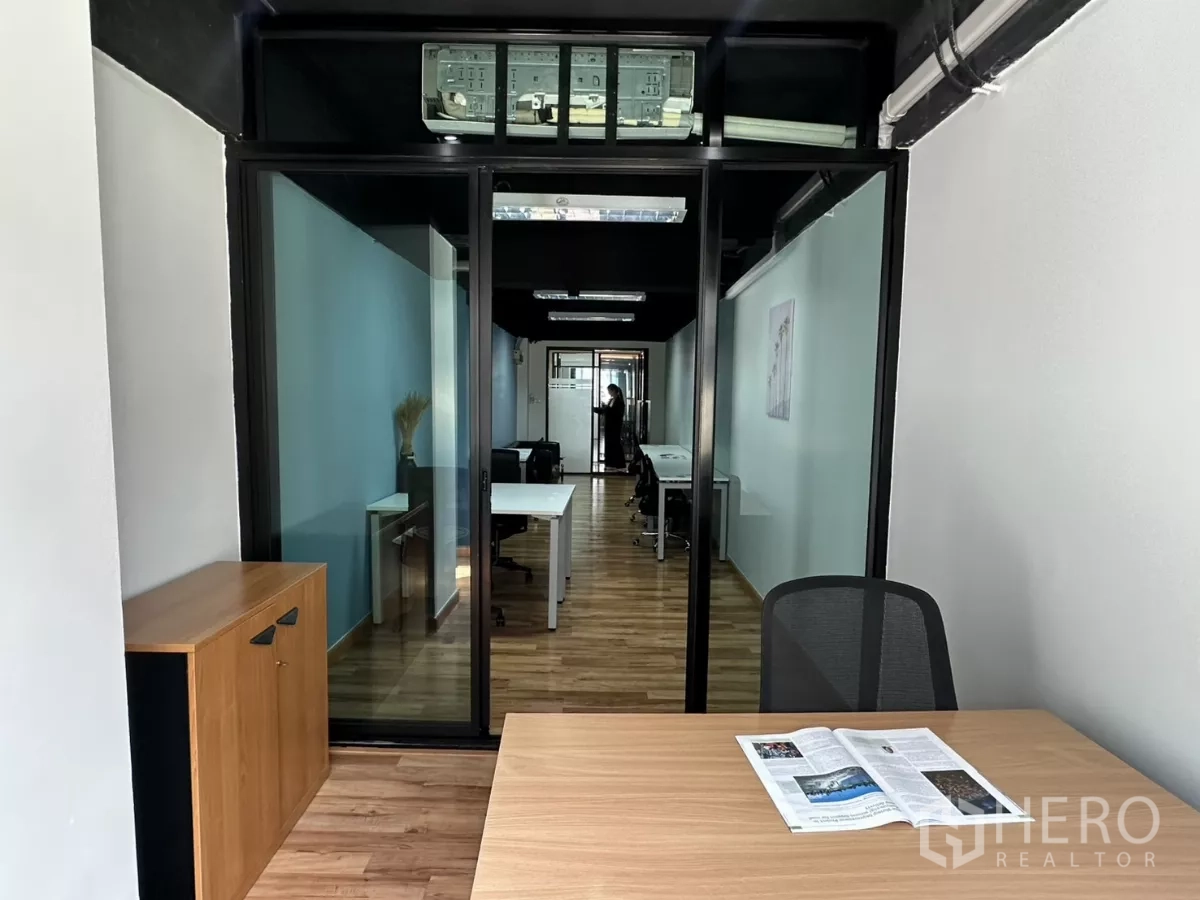 办公空间 出租在Watthana, Bangkok - 玻璃隔断会议室，面向开放式办公区，木质地板与现代办公家具。