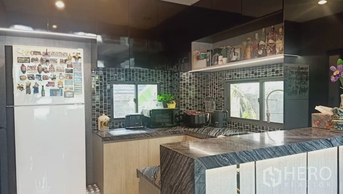 Detached House for rent or sale in Khan Na Yao, Bangkok - U-shaped kitchen with mosaic backsplash, marble-look counters and windows.