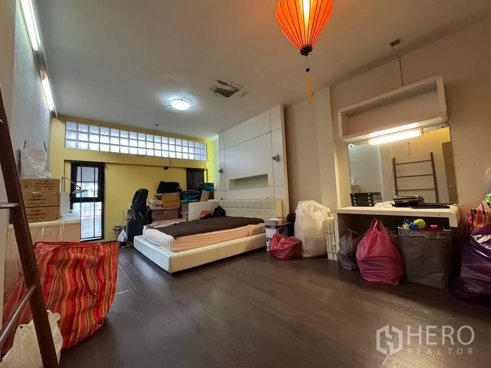 อาคารพาณิชย์ ให้เช่าในBang Rak, Bangkok - ห้องนอนกว้าง ผนังสีเหลือง เตียงเตี้ย และโคมแขวนสไตล์เอเชีย