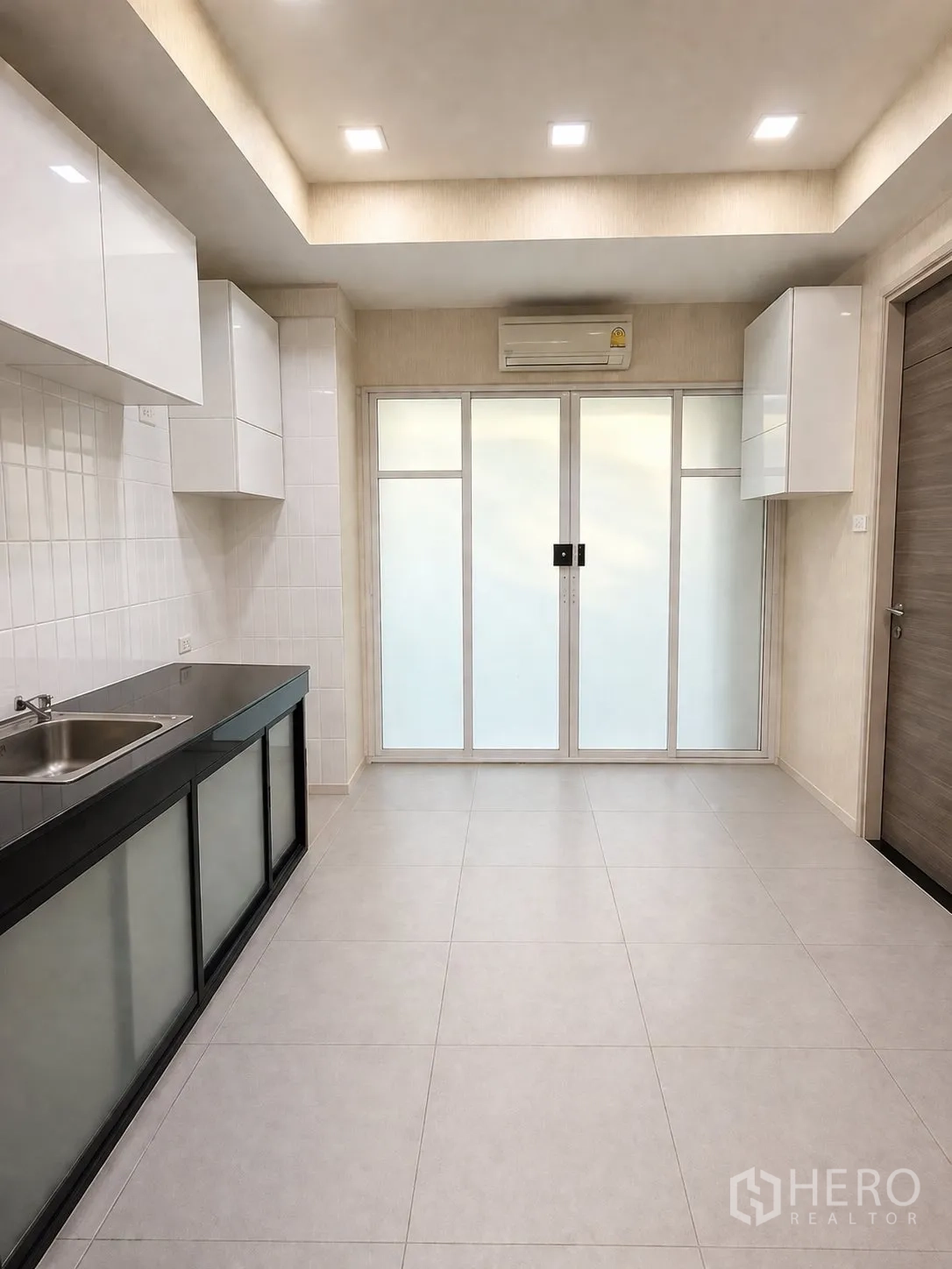 家庭办公室 for rent or sale in Yan Nawa, Bangkok - 第二个茶水间，白色柜体、推拉玻璃门与瓷砖地面。