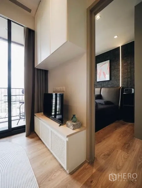 Condominium for rent - TV console by the balcony with doorway leading to a dark-tone bedroom.