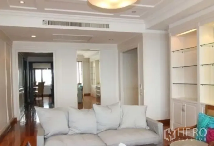 Condominium for rent in Sathon, Bangkok - Bright living room with recessed ceiling, built‑in shelves and a sofa facing a hallway in a Sathon condominium.
