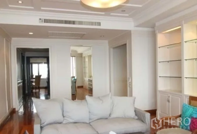 Condominium for rent in Sathon, Bangkok - Bright living room with recessed ceiling, built‑in shelves and a sofa facing a hallway in a Sathon condominium.