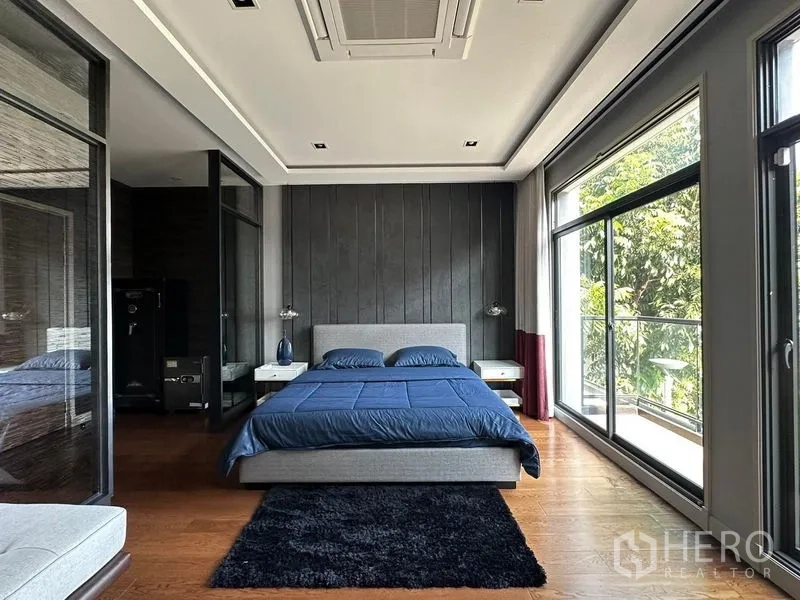 Detached House for rent in Phra Khanong, Bangkok - Spacious master bedroom with floor-to-ceiling windows and balcony overlooking greenery.
