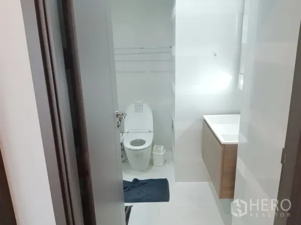 Condominium for rent in Khlong Toei, Bangkok - Bright modern bathroom with white tiles, toilet and vanity.
