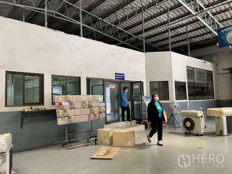 Warehouse for rent in Prawet, Bangkok - Warehouse office entrance with glazed windows and equipment beneath a metal roof.