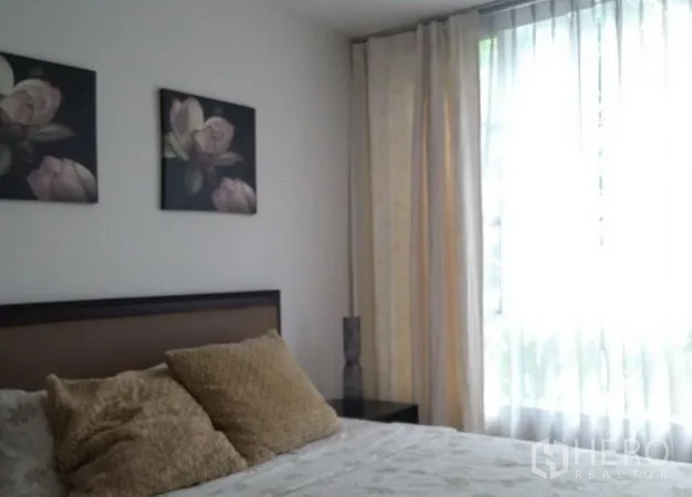 公寓 出租在Khlong Toei, Bangkok - 第二卧室设棕色床头、花卉挂画和高窗薄帘。