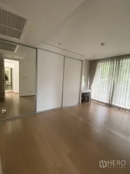 公寓 出租在Pathum Wan, Bangkok - 卧室设推拉镜柜与梳妆台，纱帘与木地板