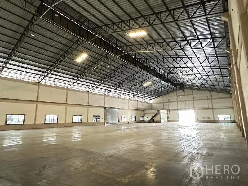 Warehouse for rent in Bang Sao Thong, Samut Prakan - Open warehouse space with skylights, steel roof trusses and an internal stair to a mezzanine office.