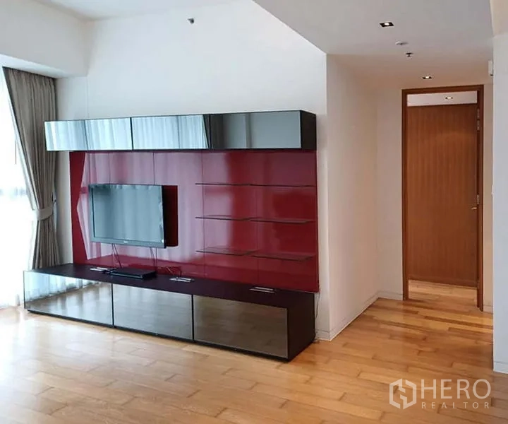 คอนโด ให้เช่าในSathon, Bangkok - ผนังทีวีสีแดงเงาพร้อมชั้นวางและจอติดผนัง ข้างหน้าต่างมีผ้าม่าน